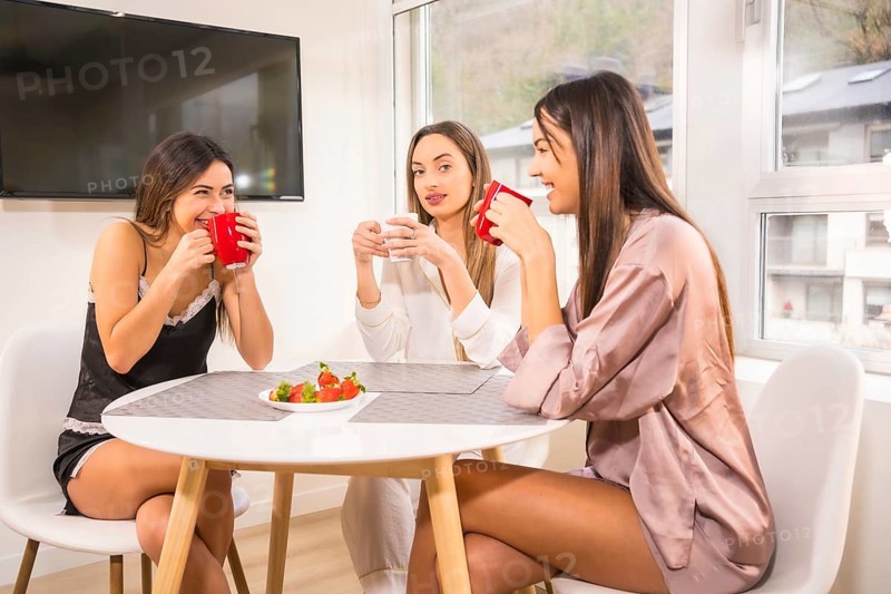 Lifestyle of Caucasian friends on vacation in a hotel having breakfast, dressed in nightwear and drinking coffee