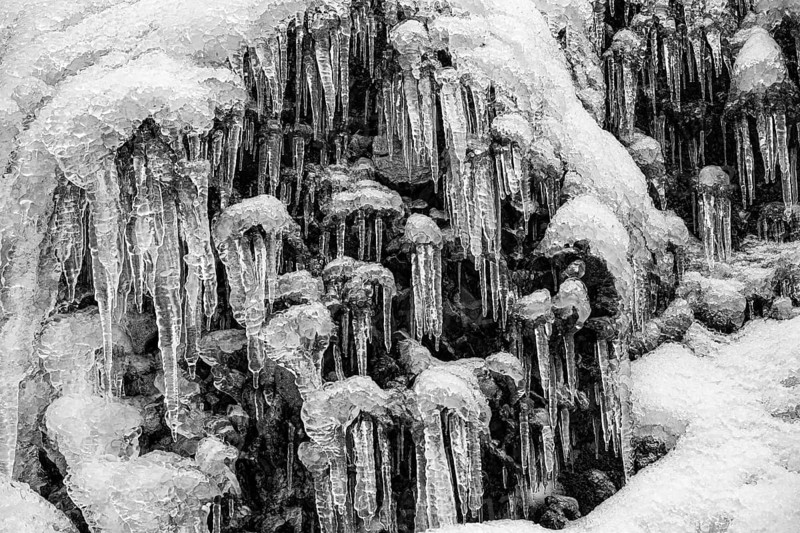Icicles on the rock face at Skogafoss waterfall, black and white photo, Sudurland, Iceland, Europe