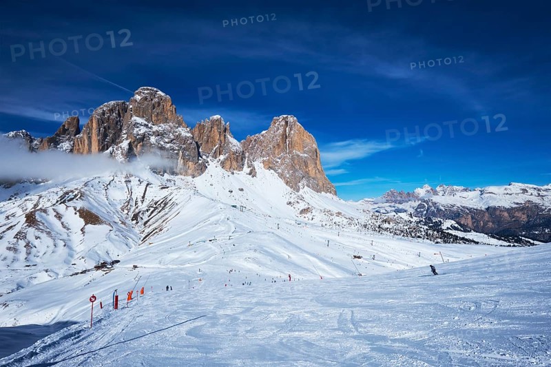 View of a ski resort piste with people skiing in Dolomites in Italy