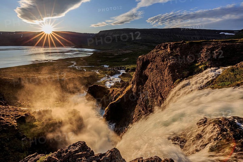 Waterfall backlit by midnight sun in front of mountains and coast, summer, Dynjandi, Westfjords, Iceland, Europe