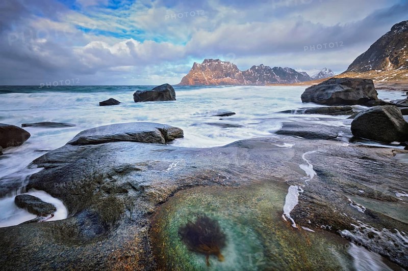 Rocks on beach of fjord of Norwegian sea in winter with snow. Utakliev beach, Lofoten islands, Norway, Europe