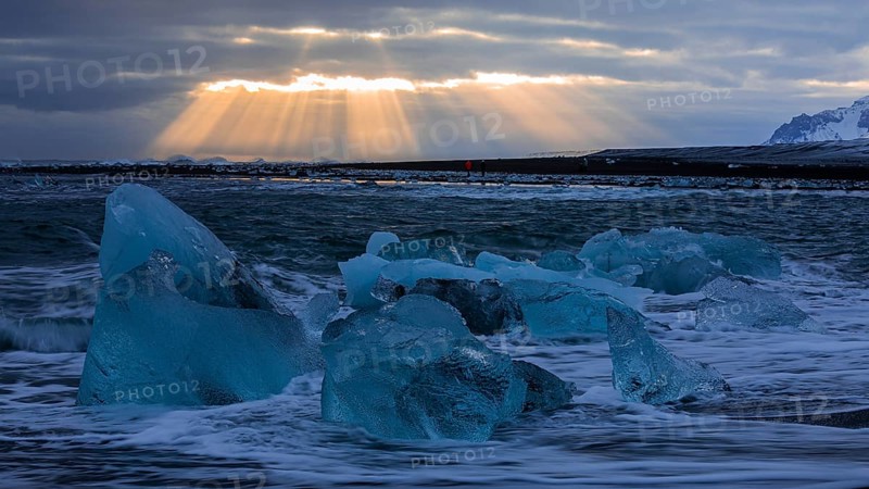 Waves breaking on icebergs on the black beach of Breidamerkursandur, sunset, near Jökullsarlon, Sudurland, Iceland, Europe