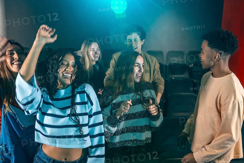 Cheerful young people dancing and having fun at a movie disco event, enjoying music and togetherness in a vibrant cinema atmosphere