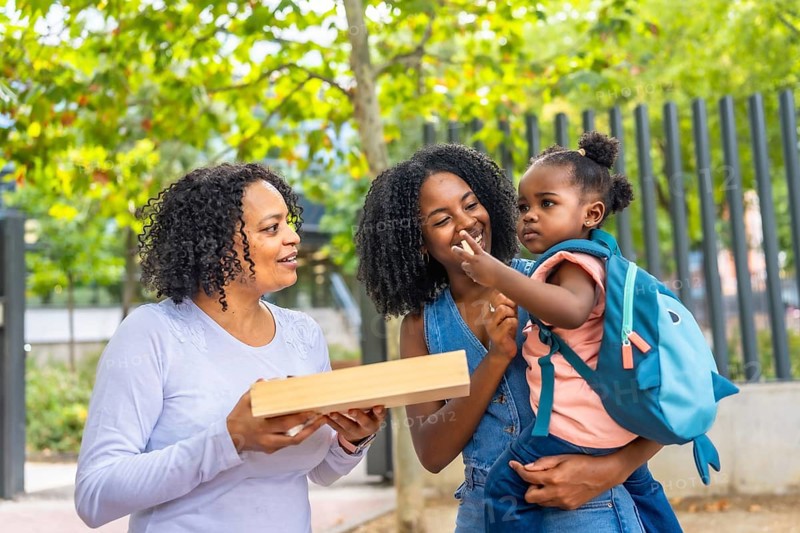 Cute african girl with her mother and grandmother in the park after school day