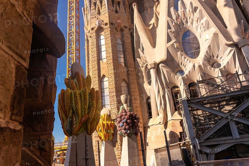 Colorful ceramic pinnacles and construction crane are visible at sagrada familia in barcelona, a unesco world heritage site