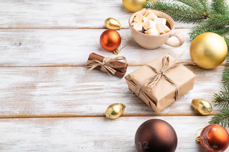 Christmas or New Year composition. Decorations, box, golden balls, cinnamon, fir and spruce branches, cup of coffee, on a white wooden background. Side view, copy space