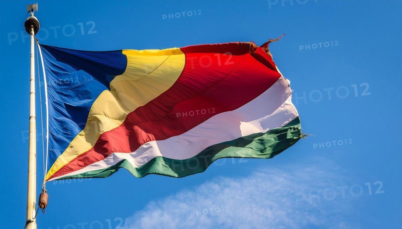 The flag of Seychelles, fluttering in the wind, isolated against a blue sky