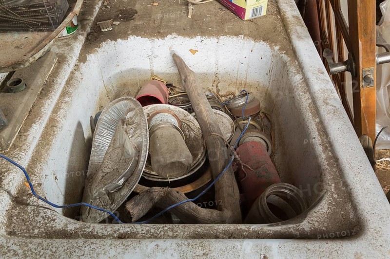 Unwashed dishes and other objects in dirty white sink inside an old barn, Quebec, Canada, North America