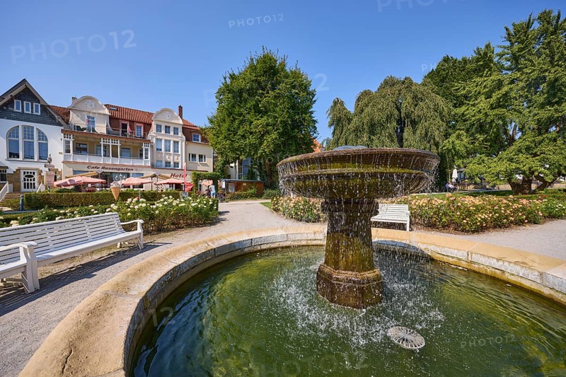 Fountain with benches, trees and houses under a cloudless blue sky in Bad Salzuflen, Lippe district, North Rhine-Westphalia, Germany, Europe