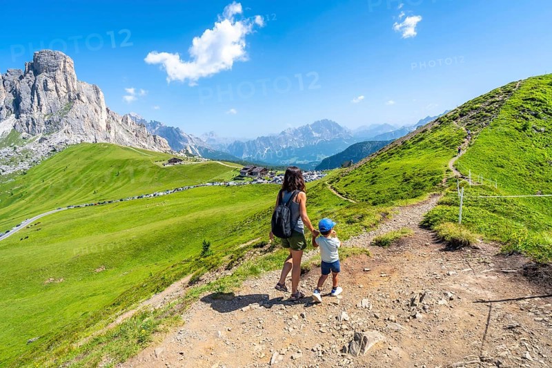 Mother and son enjoying the scenic view of the giau pass in the italian dolomites during a summer hike