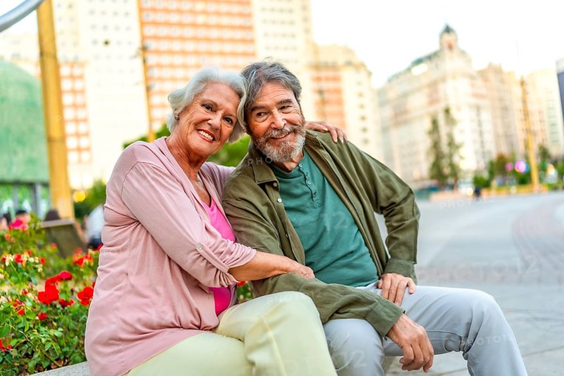 Senior caucasian male and female lovers sitting on city bench together
