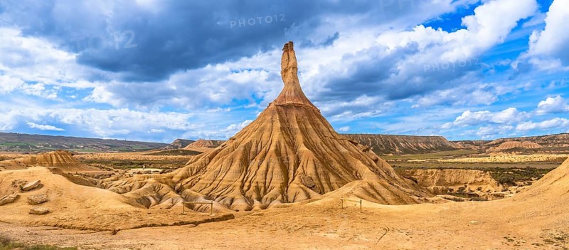 Eroded rock formations standing tall in the bardenas reales desert in navarre, spain, under a dramatic cloudy sky