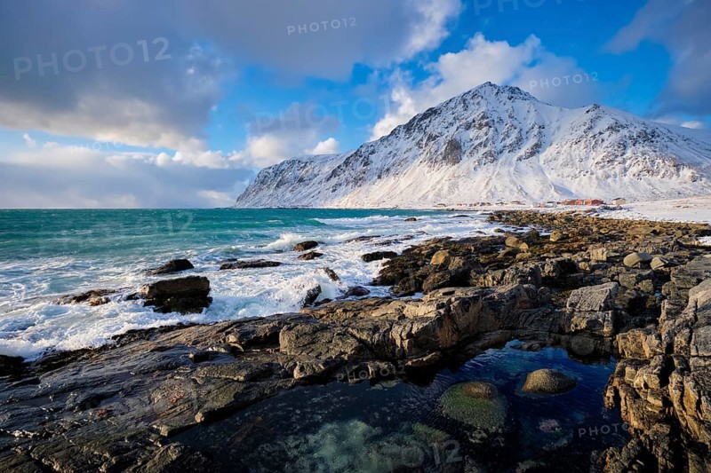 Beach of Norwegian sea on rocky coast in fjord on sunset in winter. Vareid beach, Lofoten islands, Norway, Europe