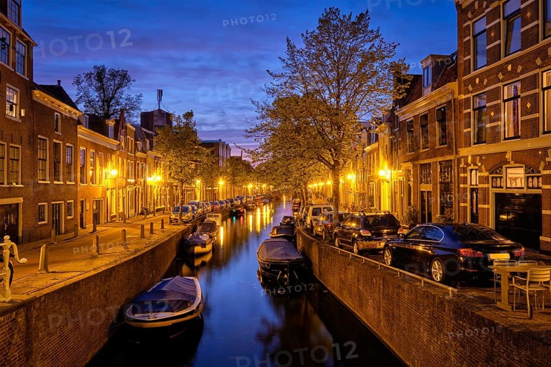 Typical Netherlands city view, canal with boats and houses illuminated in the evening. Haarlem, Netherlands