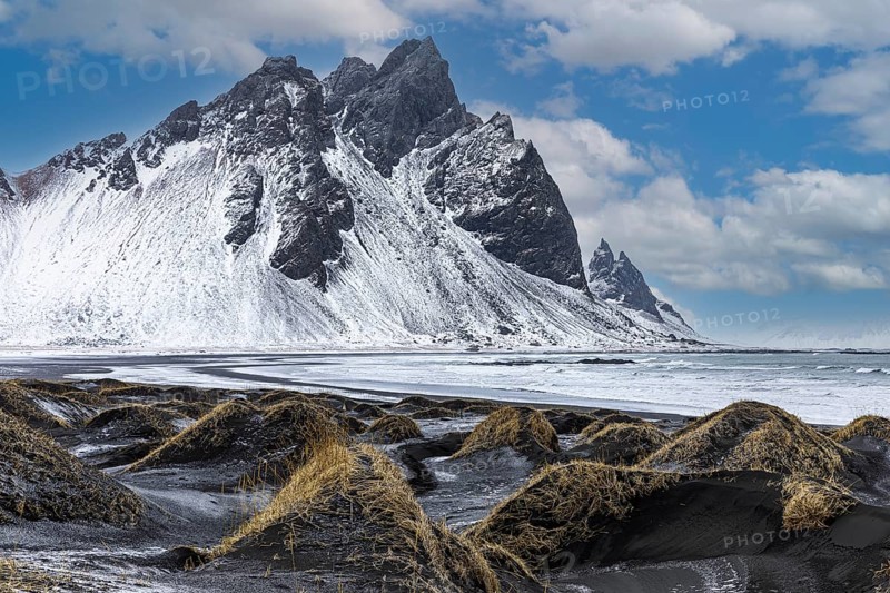 Black sand dunes with reed remains, behind them snowy rocky slopes of Vestrahorn, near Höfn, Sudausturland, Iceland, Europe