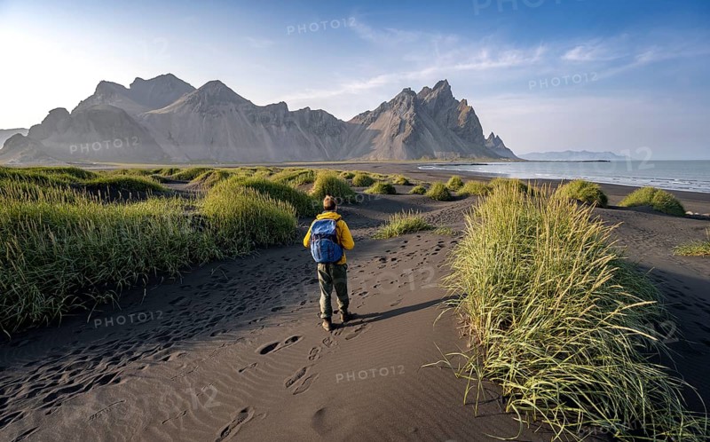 Tourist on a sand dune, Black beach with volcanic sand, Sand beach, Dunes with grass, Stokksnes headland, Klifatindur mountain range, Austurland, East Iceland, Iceland, Europe