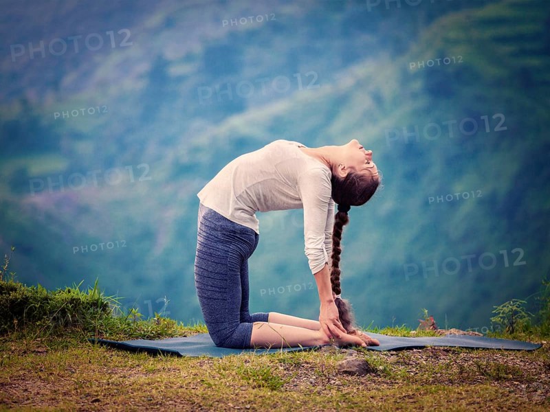 Yoga, outdoors young beautiful slender woman yoga instructor doing camel pose Ustrasana asana exercise outdoors. Vintage retro effect filtered hipster style image