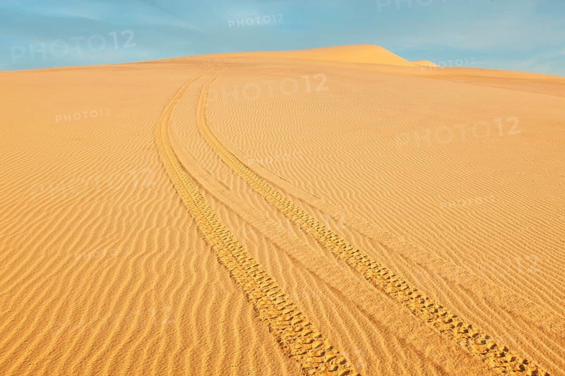 All-terrain vehicle (ATV) tracks in white sand dunes on sunrise, Mui Ne, Vietnam. Dunes around Bao Trang (White Lake near Phan Thiet) are a major tourist attraction at Mui Ne