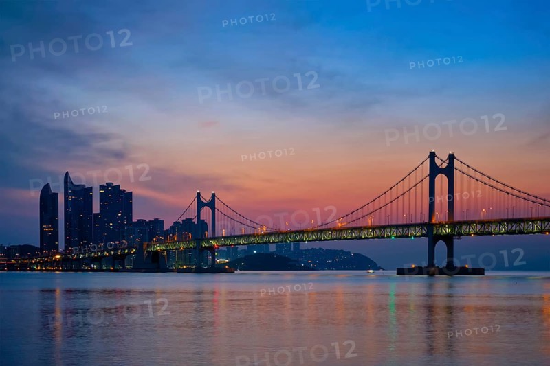 Gwangan Bridge on sunrise with skyscrapers and dramatic sky. Busan, South Korea, Asia