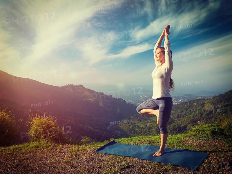 Yoga practice outdoors, woman practices balance yoga asana Vrikshasana tree pose in Himalayas mountains outdoors in the morning. Himachal Pradesh, India. Panorama. Vintage retro effect filtered hipster style image