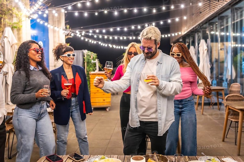 Cool man dancing with multiracial woman at night party in the roof of a bar at city