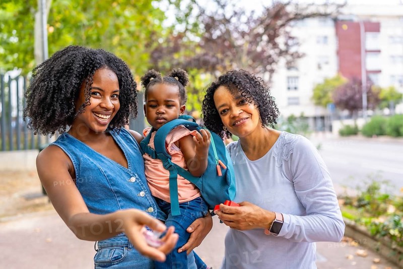 Portrait of three generation african female family in the park smiling at camera standing together