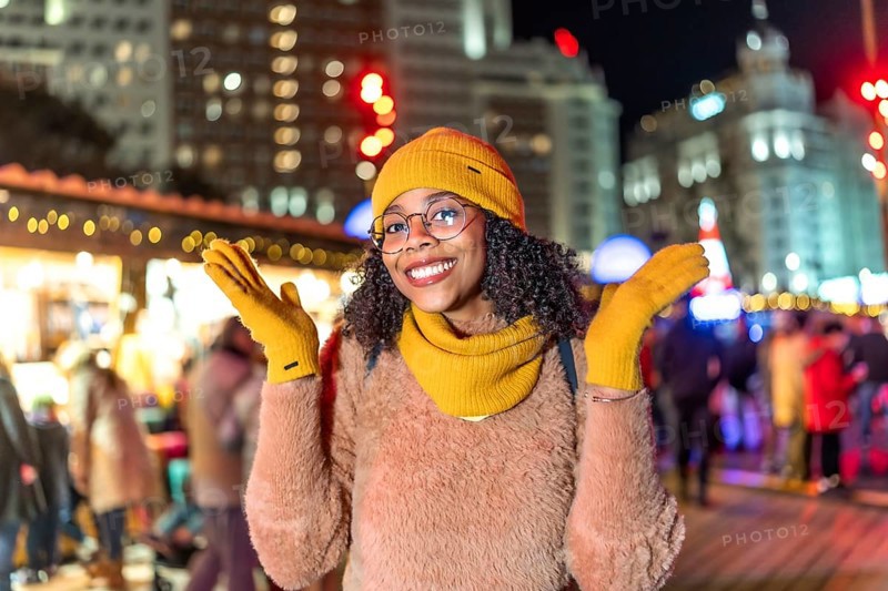 Young woman wearing yellow winter clothes enjoying christmas market in plaza de espana, madrid, at night