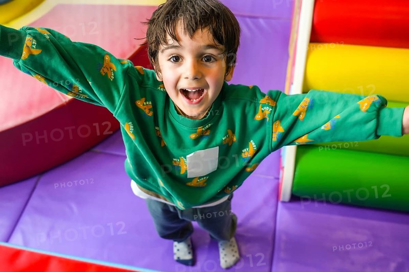 Preschooler enjoying playtime in colorful indoor playground, expressing pure happiness and excitement