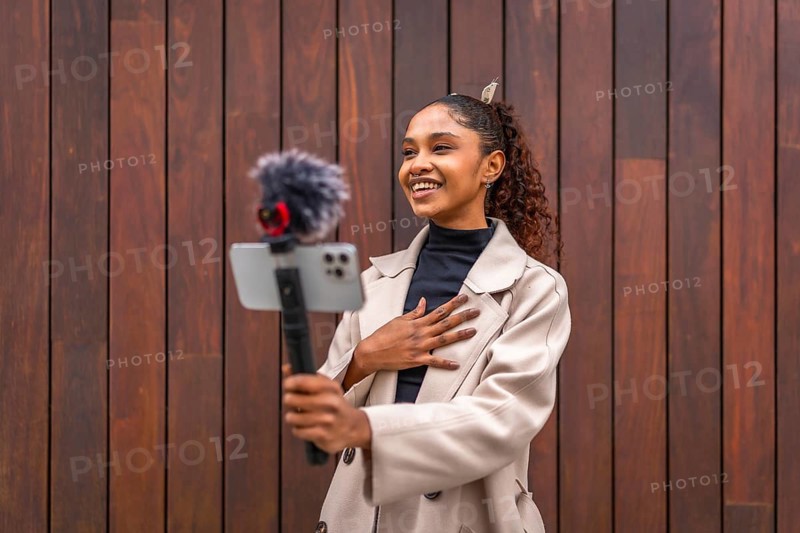 African american beauty woman vlogger smiling recording a new video blog in the city