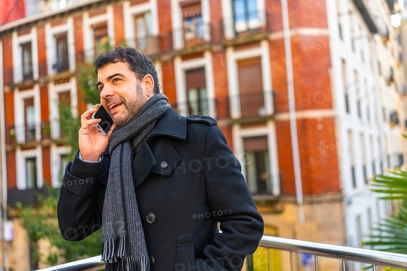 Adult caucasian man in elegant warm clothes talking to the mobile standing in the city