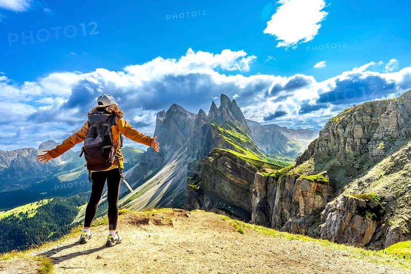 Hiker with open arms enjoying the breathtaking view of the odle mountains in seceda, dolomites, italy