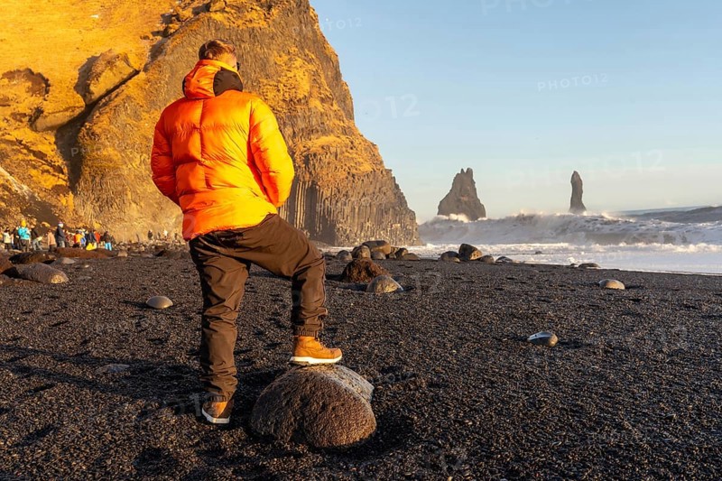 A tourist looking at the beautiful Reynisfjara Black Sand Beach in Iceland in winter