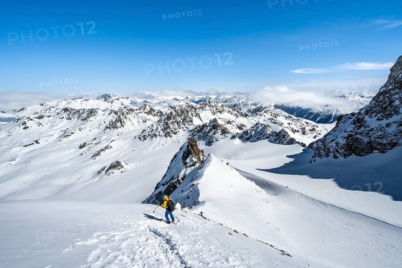 Mountaineer with ice axe and crampons, ascent through steep snowfield to Piz Kesch or Piz d'Es-cha in winter, view of mountain panorama with Vadret da Porchabella glacier, Albula Alps, Rhaetian Alps, Grisons, Eastern Switzerland, Switzerland, Europe