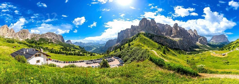 Breathtaking panorama of the dolomites in summer, showcasing lush green valleys, rugged peaks, and a clear blue sky, creating a stunning alpine landscape
