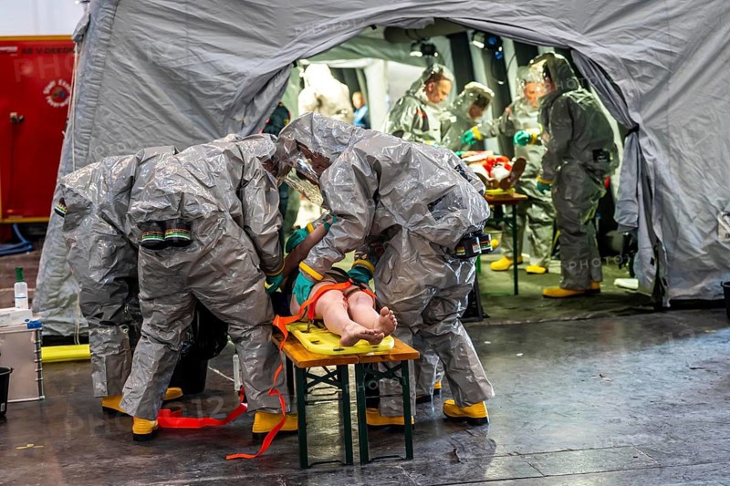 Decontamination of injured persons after an assumed accident involving hazardous substances, fire brigade and aid organisations practise setting up and operating a decontamination station, injured persons are sighted and then washed in a special shower tent to remove possible hazardous substances and chemicals in order to avoid further injuries, the emergency services wear special, ventilated protective suits, large-scale exercise by the Essen fire brigade