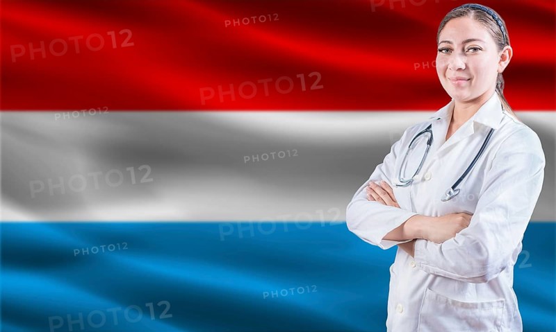 Female doctor on Luxembourg flag. Doctor with crossed arms on Luxembourg flag. Luxembourg health and care concept