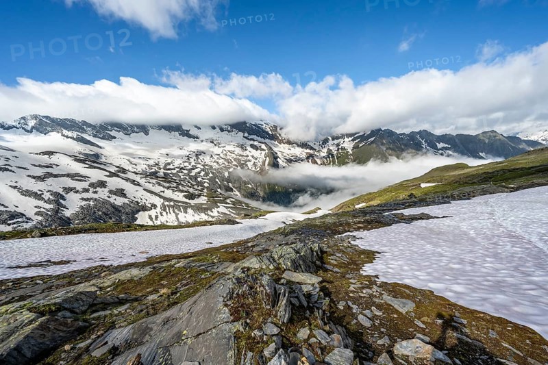 Mountain landscape with snowfields and high fog in the valley, behind summit Hoher Weißzint and Hochsteller with glacier Schlegeiskees, Berliner Höhenweg, Zillertal Alps, Tyrol, Austria, Europe