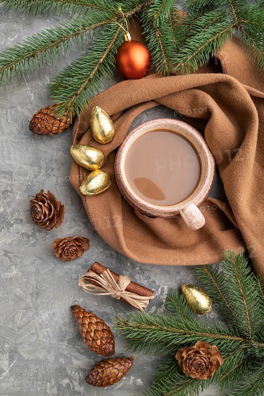 Christmas or New Year composition. Decorations, cones, cinnamon, fir and spruce branches, cup of coffee, wool scarf on a gray concrete background. Top view, close up, flat lay