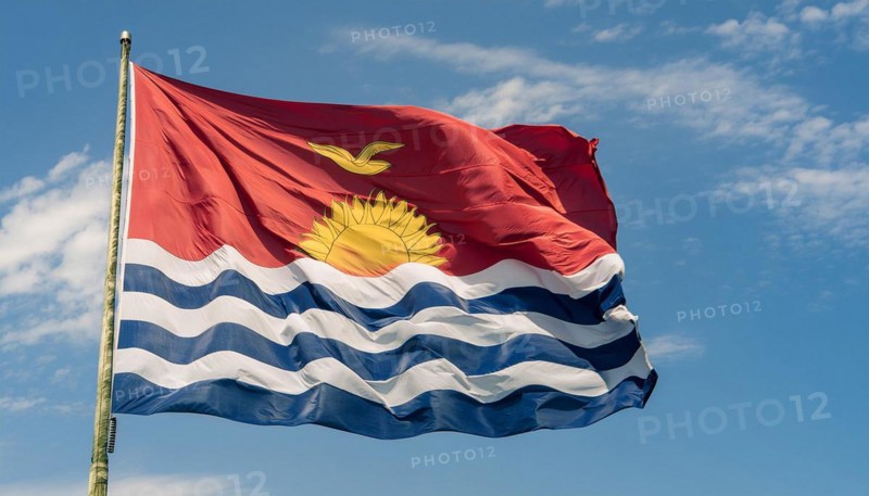The flag of Kiribati, Polynesia, flutters in the wind, isolated against a blue sky