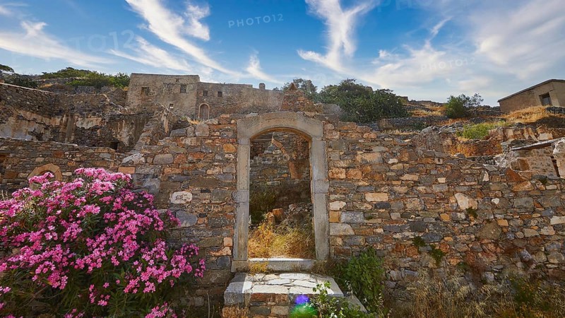 Pink flowers blooming at a stone archway amidst ancient ruins under a blue sky, Venetian Sea Fortress, Leper Island, Spinalonga, Elounda Bay, Mirabello Bay, East Crete, Crete, Greek Islands, Greece, Europe