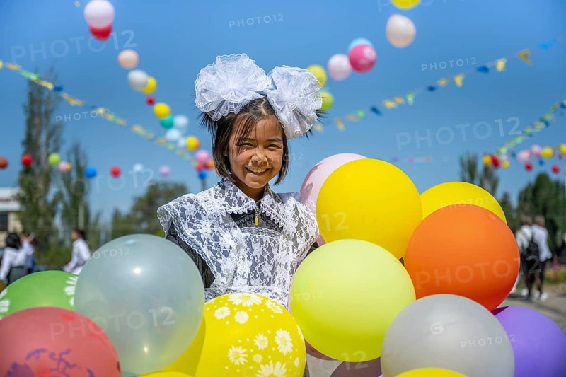Happy schoolgirl with colourful balloons on the first day of school, Issyk-Kul region, Kyrgyzstan, Asia