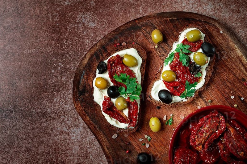 Sandwich with cream cheese, dried tomatoes, olives, breakfast, top view