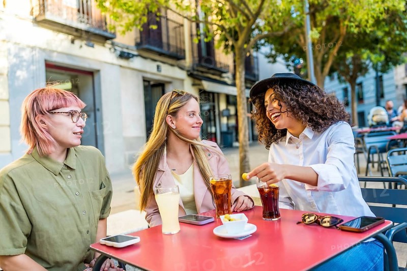 Tourist eating tapas and drinking sodas in outside bar sitting on table in the street