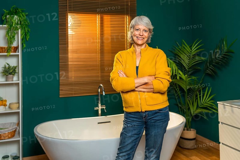 Casual caucasian mature woman standing with arms crossed on a modern bathroom