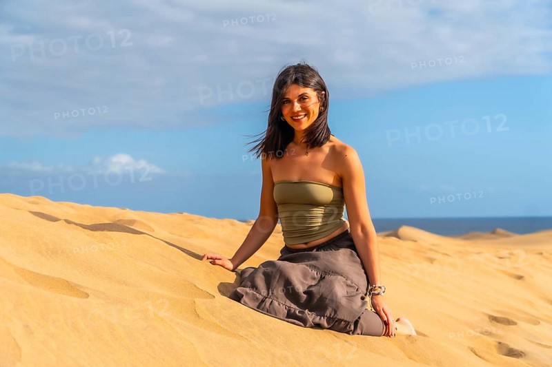 Young woman relaxing and enjoying a sunny day sitting on the sand of the maspalomas dunes in gran canaria, spain