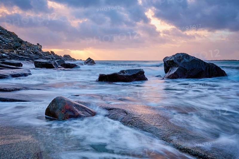 Rocks on beach of fjord of Norwegian sea in winteron sunset. Utakliev beach, Lofoten islands, Norway, Europe