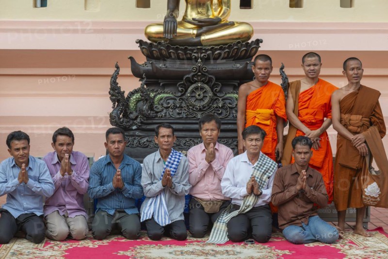 Monks and Laotians in front of a Buddha statue, Bhumispara-mudra, Buddha Gautama at the moment of enlightenment, Wat Ong Teu, Vientiane, Laos, Asia
