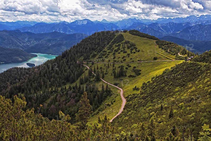 Panoramic view from the Herzogstand of wooded mountains and a winding hiking trail, with Lake Walchensee in the background, Kochel am See, Bavaria, Germany, Europe