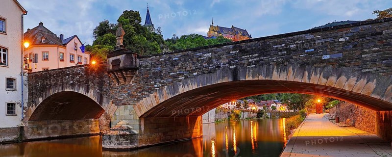 Town view of Vianden with the old stone bridge over the river Our and the castle in the evening, Grand Duchy of Luxembourg