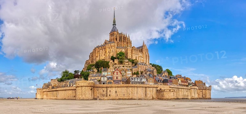 Impressive abbey on an island in the middle of a vast sandy landscape under a blue sky, Le Mont-Saint-Michel